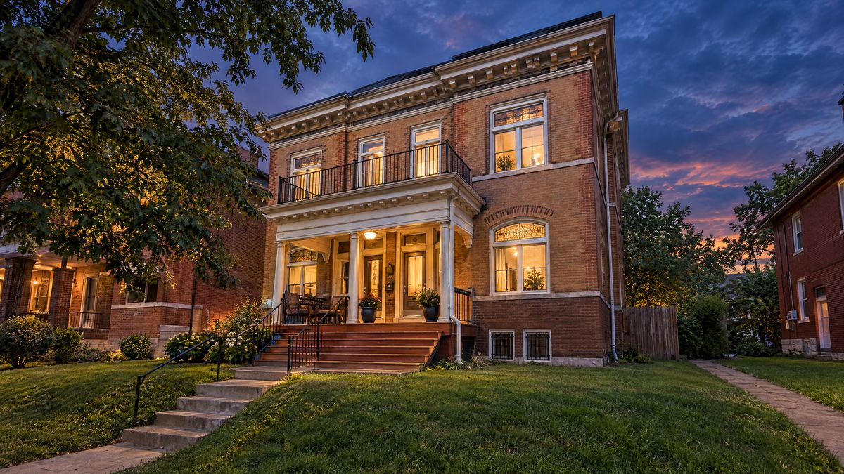 Red-brick St. Louis two-family home with a front porch at dusk